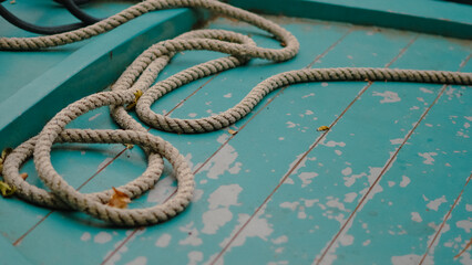 Thick marine rope lying on blue wooden boat, close-up nautical detail view