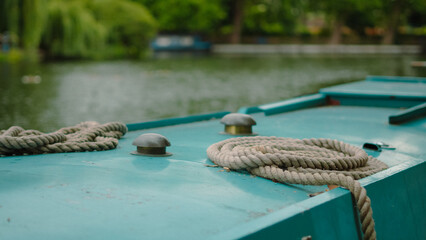 Thick marine rope lying on blue wooden boat, close-up nautical detail view
