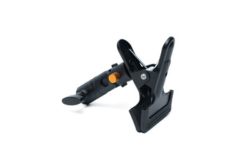 A sturdy black metal clip with an orange handle, isolated on a white background. Perfect for photography or studio lighting.