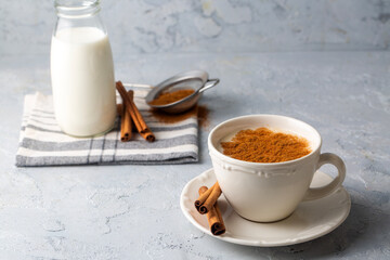 Close up white cup of salep milky hot drink of Turkey with cinnamon powder healthy spice on black wooden background (Sahlep - salep)