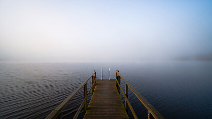 Obraz premium Wooden Pier Extending Into Misty Lake at Dawn with Calm Water dock