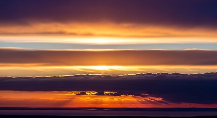 A breathtaking view of a layered sunset sky with the sun's rays breaking through dark dramatic clouds over the horizon