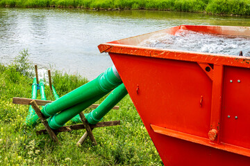 Water treatment tank near a river for waste management at a rural location during daylight hours
