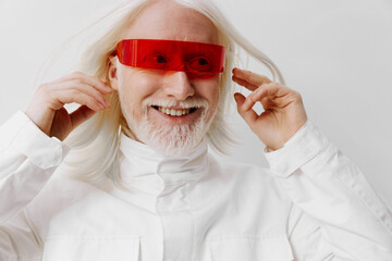 Stylish elderly man with white hair and red futuristic glasses on a minimalist gray background,...