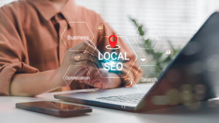 Business person working on laptop with Local SEO hologram and strategic keywords like optimization,...