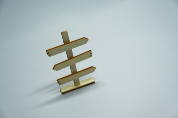 Minimalist wooden direction sign on neutral background within shadow light