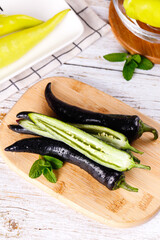 Fresh purple bell peppers cut open revealing their vibrant green interiors on a wooden cutting board with mint leaves