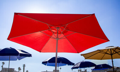 Looking up at a bright red umbrella with other umbrellas in the background