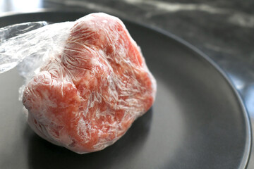 Raw minced pork in plastic wrap or cling film on a plate.