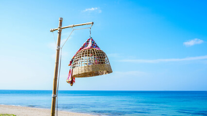 A bamboo chicken coop lamp stands on a bright beach. © christ