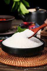 Fine Yunnan white sugar is served in a black bowl with a wooden spoon for a sweet culinary experience