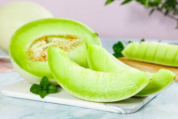 Shandong jade mushroom melon sliced on a cutting board with fresh mint leaves beside it