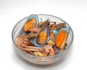 Freshly prepared seafood crustaceans such as shrimps and clams shells inside glass bowl
