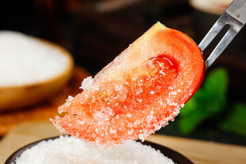 Fresh tomatoes sprinkled with white sugar create an appealing sweet and savory treat on a rustic...