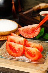 Fresh tomato slices topped with salt on a decorative plate in a rustic kitchen setting