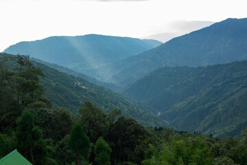 Naklejka premium Sun rays falling on Himalayan mountain range, scenic beauty of layers of mountains, Okhrey, sikkim, India. Okhrey village a remote place in Sikkim where mountain range view is enjoyed by tourists.