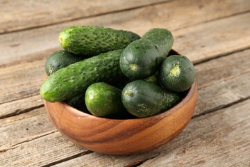 Fresh cucumbers in bowl on wooden table, closeup