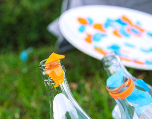 Close Up of Broken Glass Bottle with Orange and Blue Fragments on Green Grass