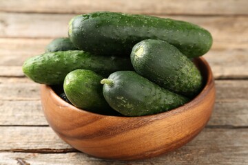 Fresh cucumbers in bowl on wooden table, closeup
