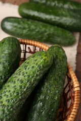 Fresh cucumbers in wicker basket on table, closeup