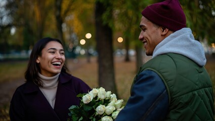 Man surprising girlfriend with bouquet of white roses in autumn park in a romantic and lovely warm scene.