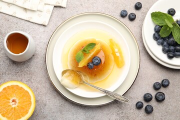 Tasty panna cotta with orange, blueberries and mint on light grey table, flat lay