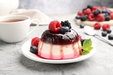 Tasty panna cotta with berries and jam on light grey table, closeup