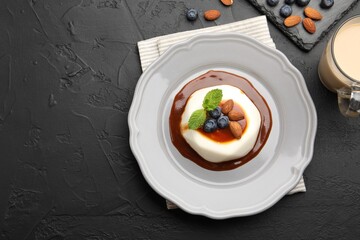 Tasty panna cotta with blueberries, almonds and sauce on black table, flat lay. Space for text