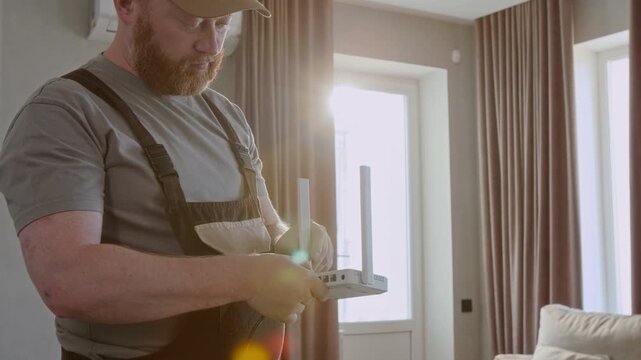 Medium shot of bearded man as maintenance worker installing internet router and plugging in cable with lens flare effect, copy space