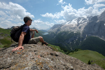 Naklejka premium Hiker resting and admiring the dolomites landscape in summer, Trentino Alto adige, Italy