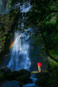 Woman with a parasol standing by Khlong Lan Waterfall, Khlong Lan National Park, Kamphaeng Phet Province, Thailand