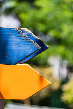 Close-up of weathered blue and yellow blank Wooden directional signs in a forest