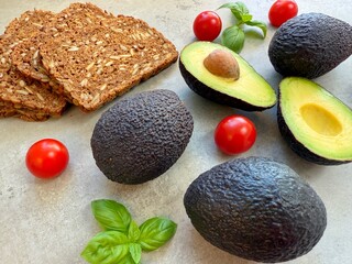 Close-up of traditional Danish rye bread with avocados, tomatoes and basil on a kitchen worktop