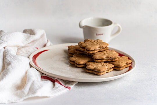 Close-up of a plate of traditional Canadian maple leaf shaped cookies with a jug of maple syrup