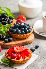 Fresh homemade berrie tarts with blueberries, blackberry and strawberries on gray background