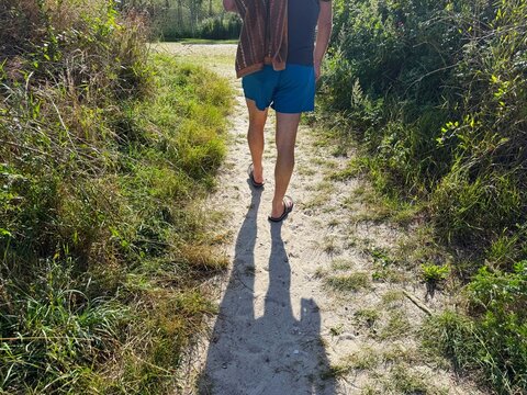 Rear view of a man on a beach in shorts carrying a towel ready to go swimming, Nordby, Samsoe, Jutland, Denmark