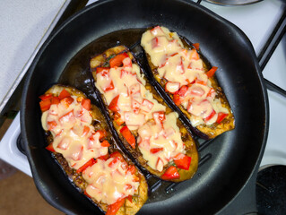 Deliciously baked eggplants topped with colorful bell peppers and melted cheese prepared in a kitchen setting