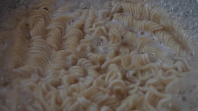 Cooking instant curly noodles in boiling water. Perfect for food blogs, cooking tutorials, and restaurant menus.