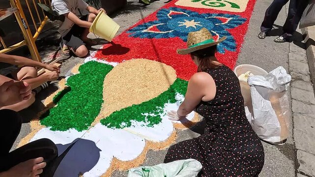 Badalona, Spain-June 25, 2024. Local artists meticulously crafting vibrant floral carpets on the streets of Catalonia, Spain, for the traditional Corpus Christi procession