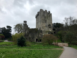 Moody, atmospheric view of Blarney Castle on a dull, overcast day, with lush green grass in the...