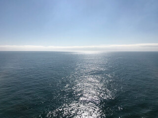 View of the sea and sky on a bright day, with the sun light reflected through the water, creating a...
