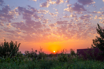 The sun sets over a vibrant landscape, painting the sky in shades of orange and purple at dawn