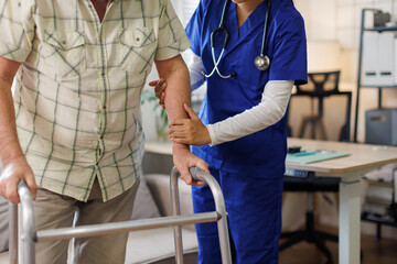 Caregiver, woman and helping with walker at nursing home for mobility support, physical therapy or...