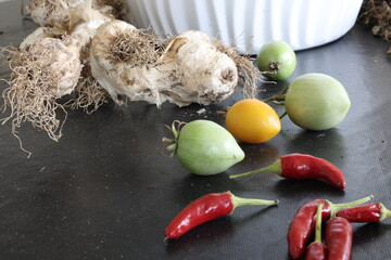 Vegetables picked from backyard home garden: green tomatoes, garlic and red chili peppers