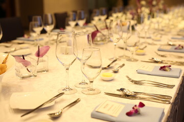 Elegant indoor banquet setup with warm lighting, neatly arranged glassware, folded napkins, and floral accents — perfect for a formal event or celebration.