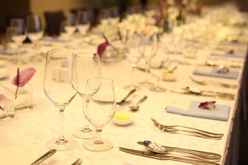 Elegant indoor banquet setup with warm lighting, neatly arranged glassware, folded napkins, and floral accents — perfect for a formal event or celebration.