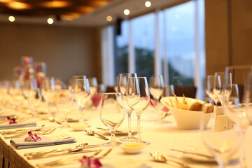 Elegant indoor banquet setup with warm lighting, neatly arranged glassware, folded napkins, and floral accents — perfect for a formal event or celebration.