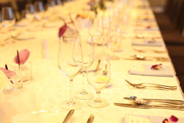 Elegant indoor banquet setup with warm lighting, neatly arranged glassware, folded napkins, and floral accents — perfect for a formal event or celebration.