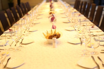 Elegant indoor banquet setup with warm lighting, neatly arranged glassware, folded napkins, and floral accents — perfect for a formal event or celebration.