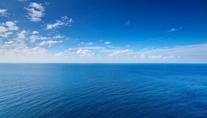 Obraz premium the vast expanse of the ocean stretches out before a clear blue sky dotted with wispy white clouds